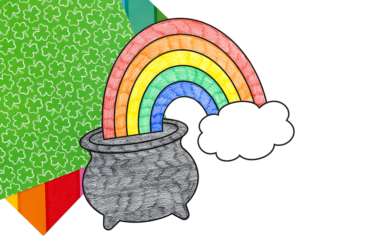 Gluing the pot, rainbow, and cloud together to assemble St. Patrick’s Day Pot of Gold Craft.