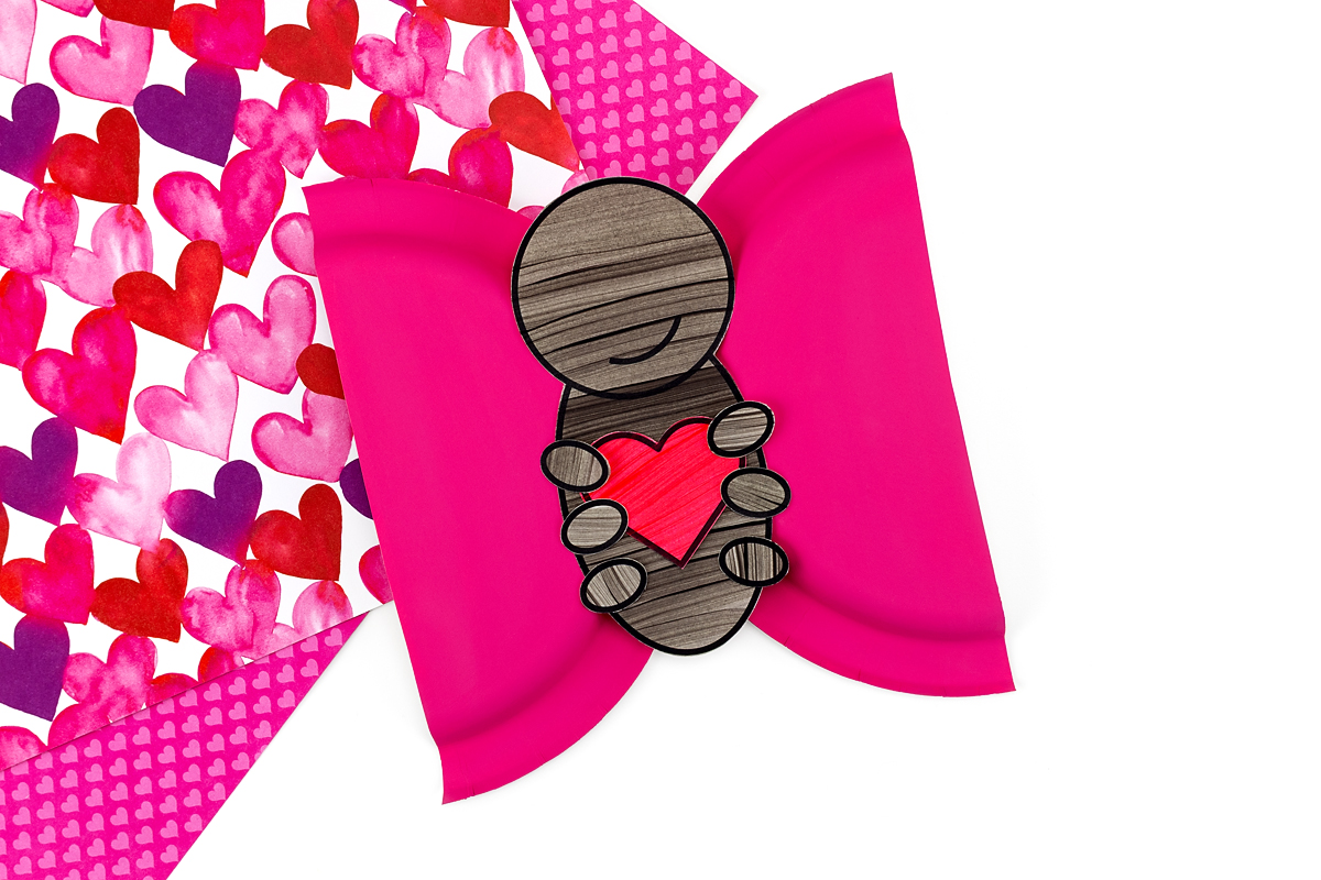 Heart shapes and legs being glued onto love bug wings as decoration.