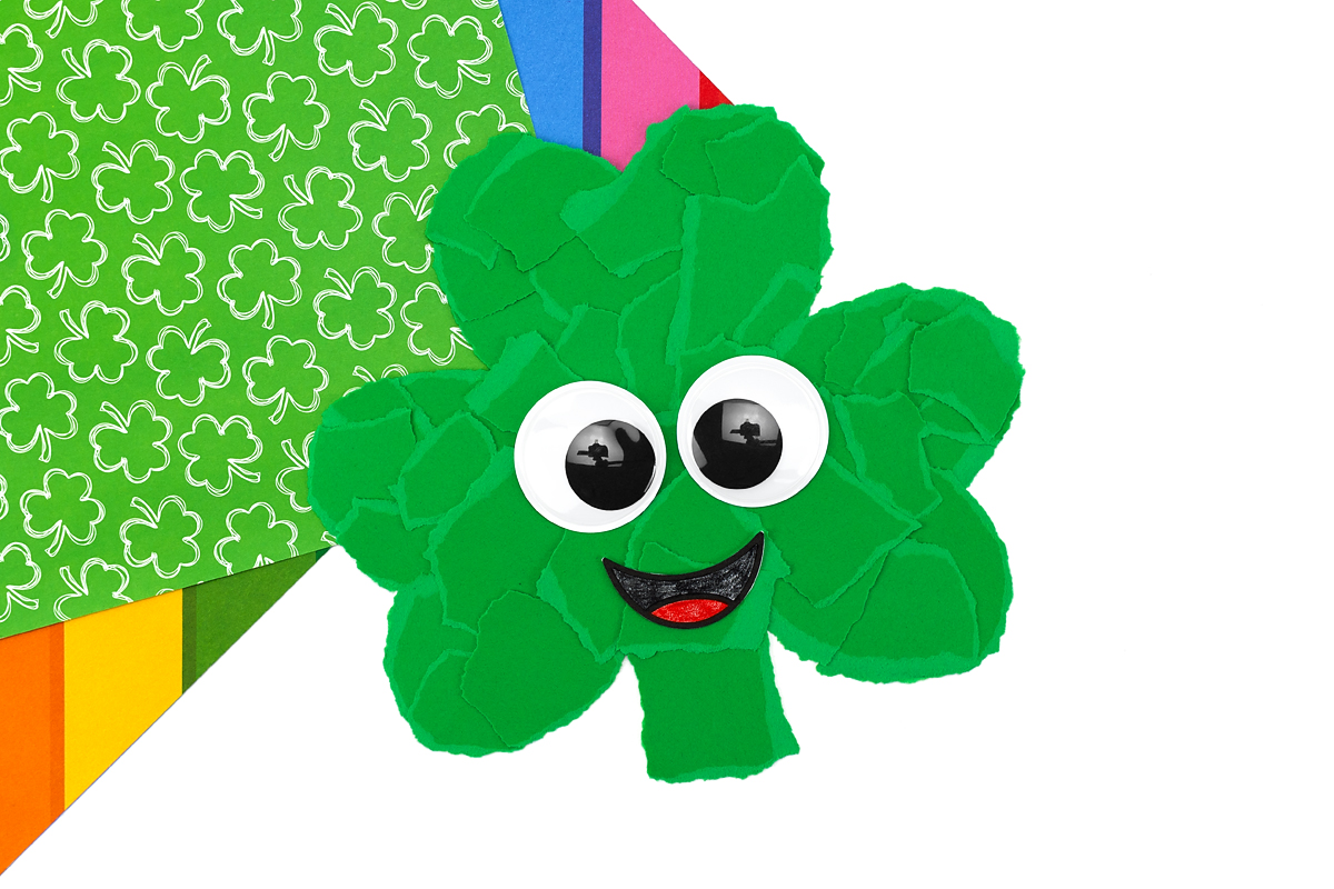 Shamrock craft with googly eyes attached and smiling mouth colored in.