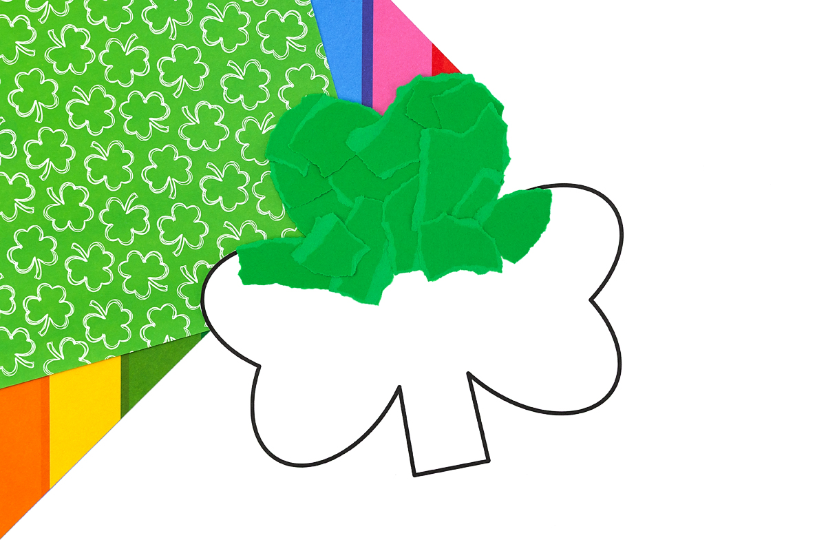 Green construction paper torn into small pieces for shamrock craft.