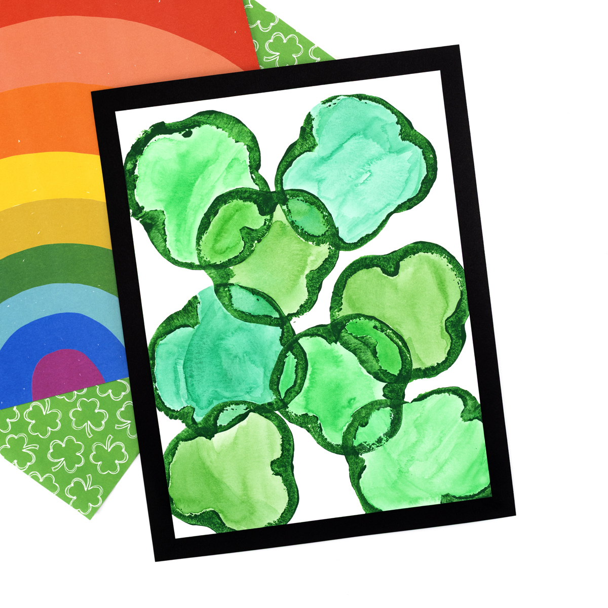 Shamrock prints filled in with watercolor paints, showing vibrant green and blended colors.