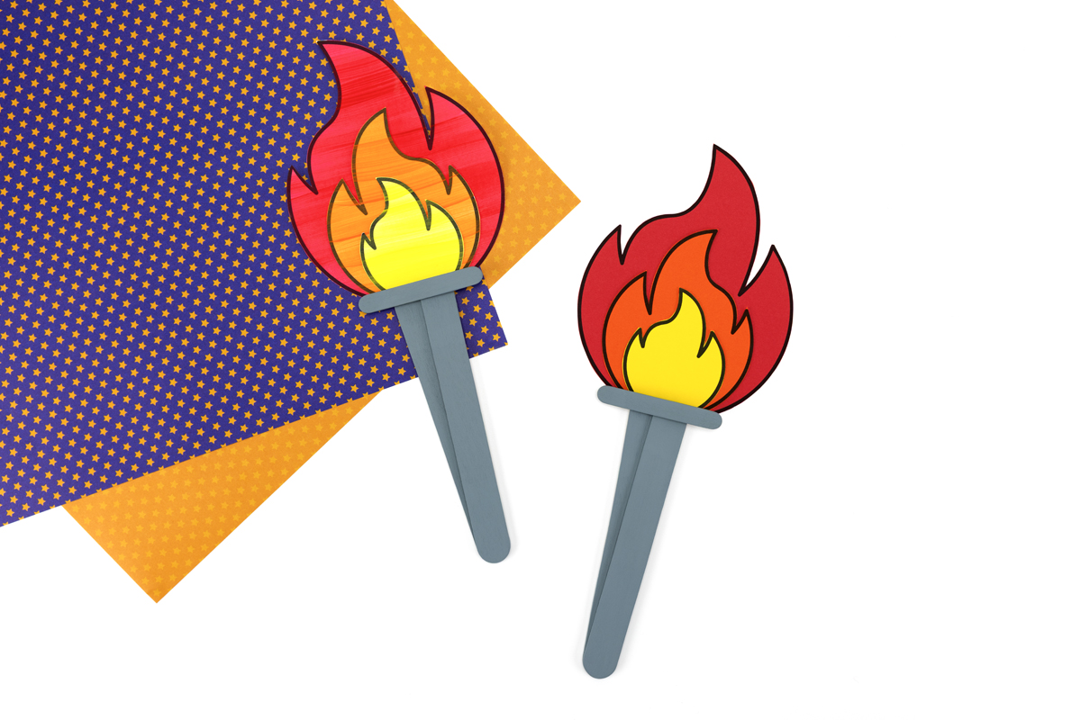 Two torches on a table. One is painted, the other is made with colored cardstock.