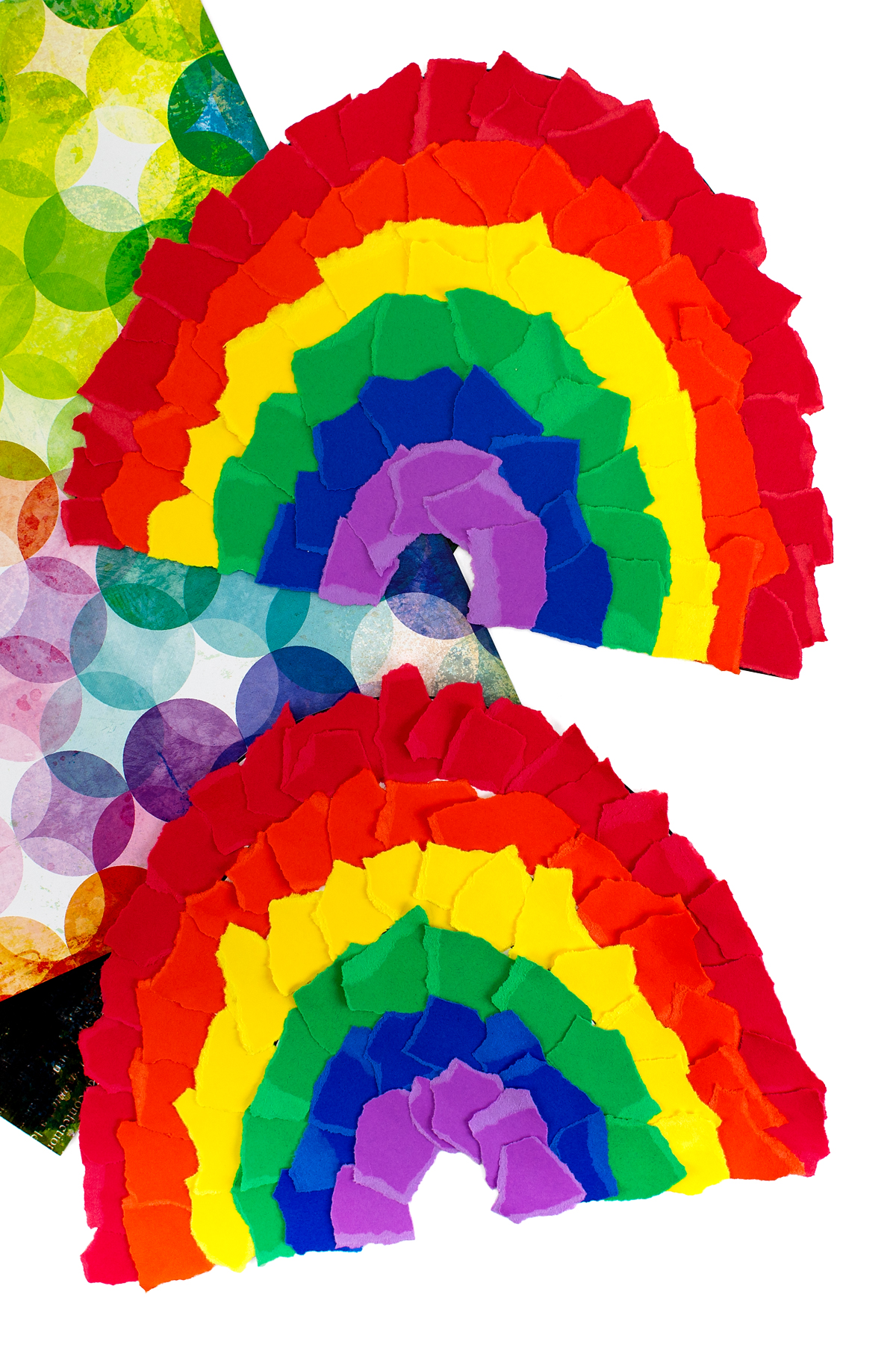 A colorful paper rainbow made from curved strips of red, orange, yellow, green, blue, and purple paper.