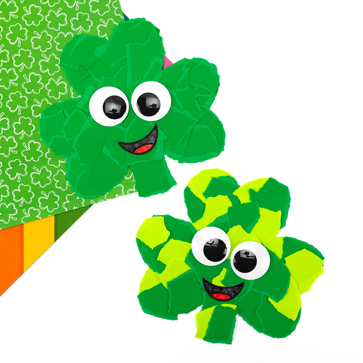 Two torn paper shamrock crafts with different green shades and googly eyes displayed together.