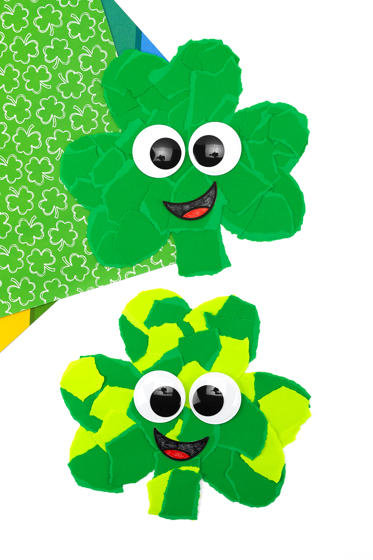 Pair of torn paper shamrock crafts with layered green paper texture and smiling faces.