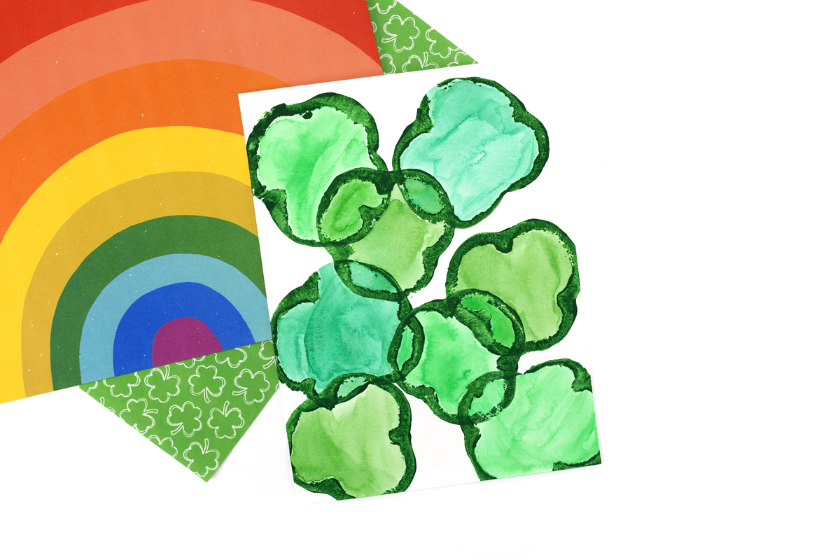 Shamrock prints filled in with watercolor paints, showing vibrant green and blended colors.