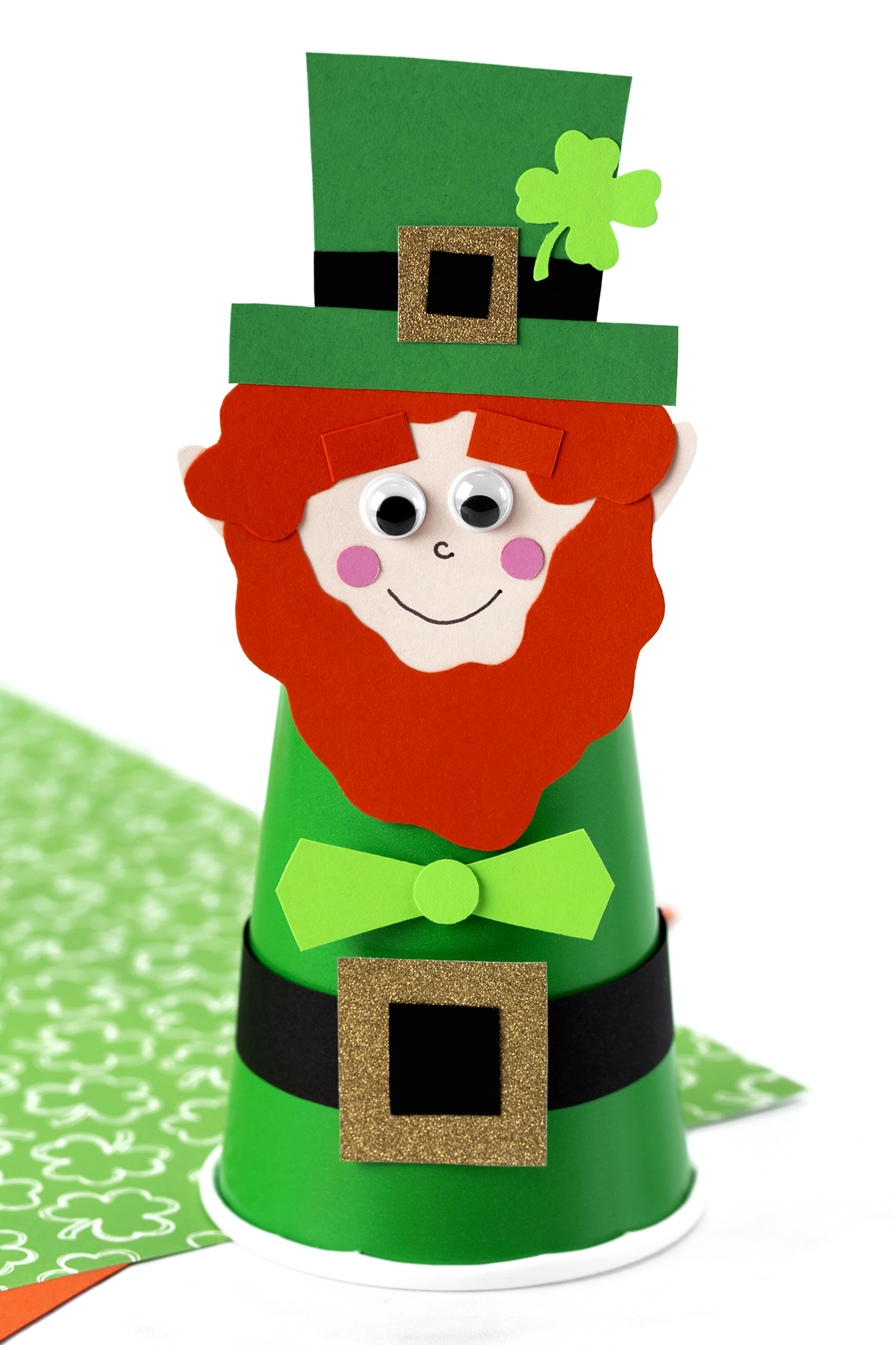 A small leprechaun made from a green paper cup, with paper hat and face details.