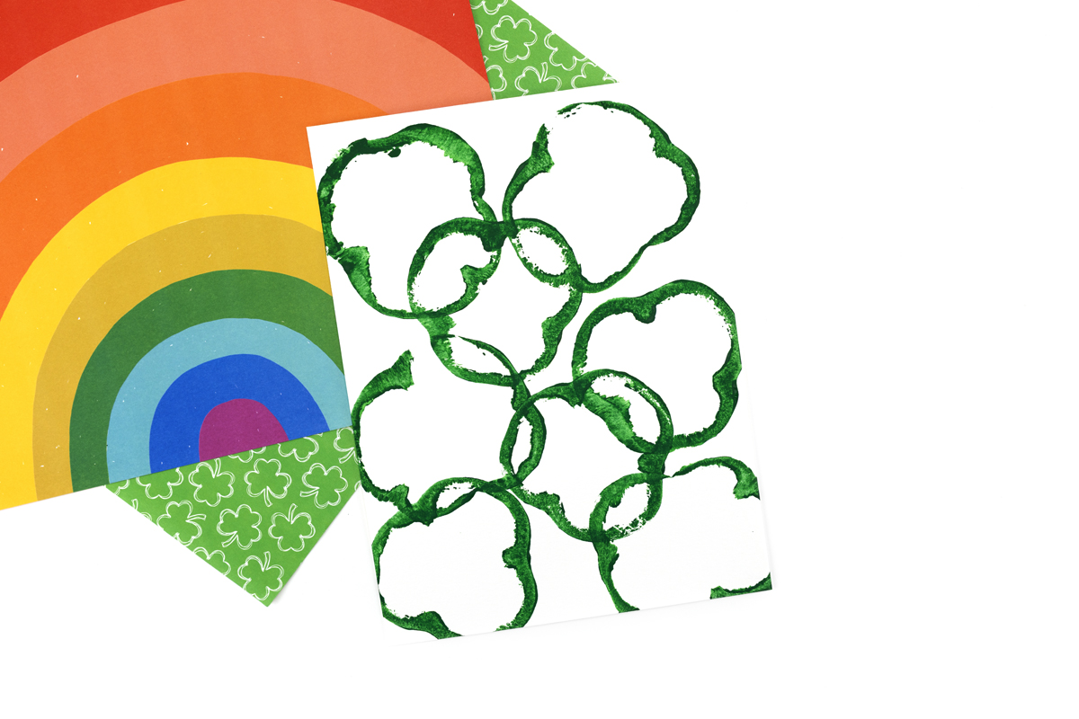 Several green shamrock prints on white paper, ready to be colored with watercolors.