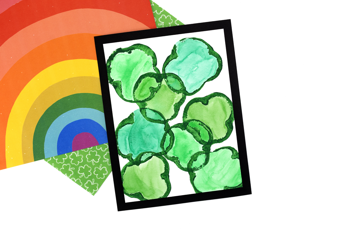 Completed green pepper shamrock prints, colored with watercolors and mounted on black construction paper.