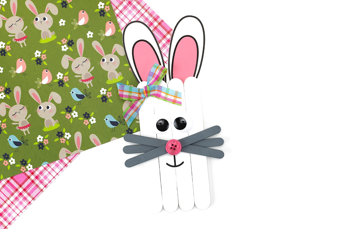 Completed popsicle stick bunny craft with white painted sticks, paper ears, and gray whiskers.