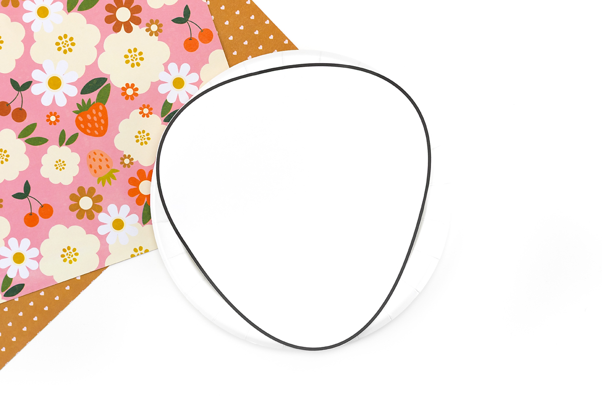 Paper plate with strawberry template traced and cut into a strawberry shape.