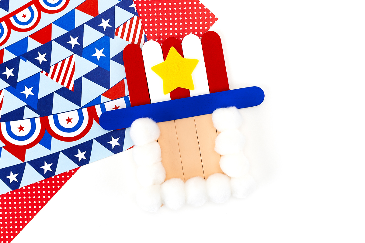 Uncle Sam popsicle stick craft with a yellow felt star glued to the red and white striped hat.