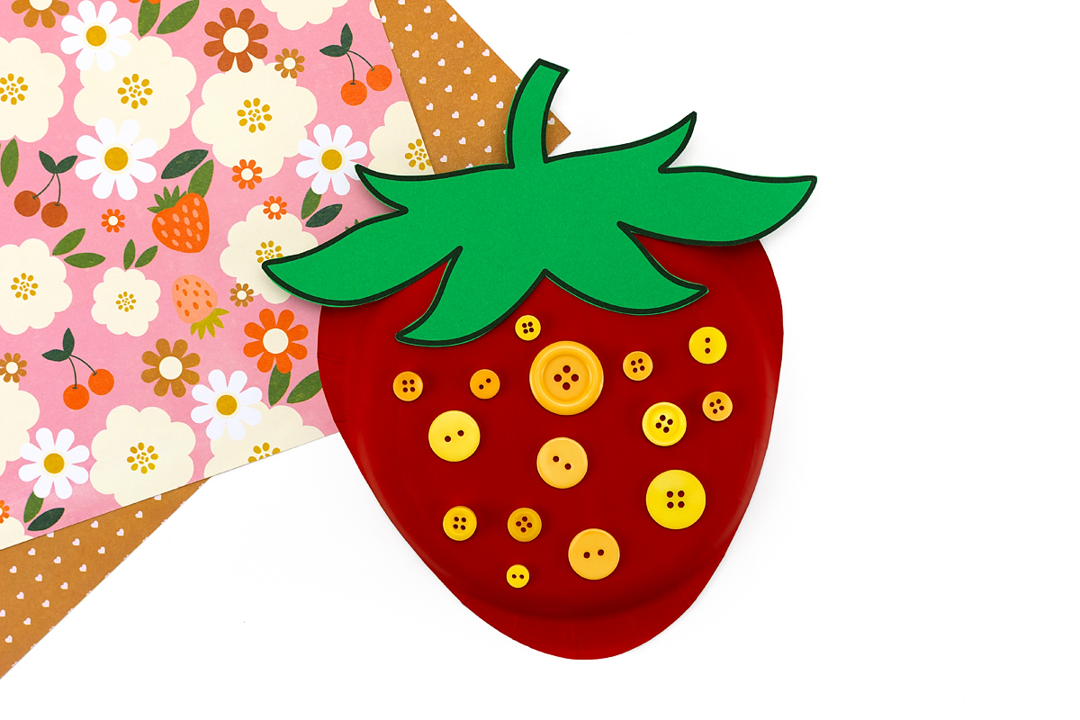 Yellow buttons glued onto paper plate strawberry as seeds.