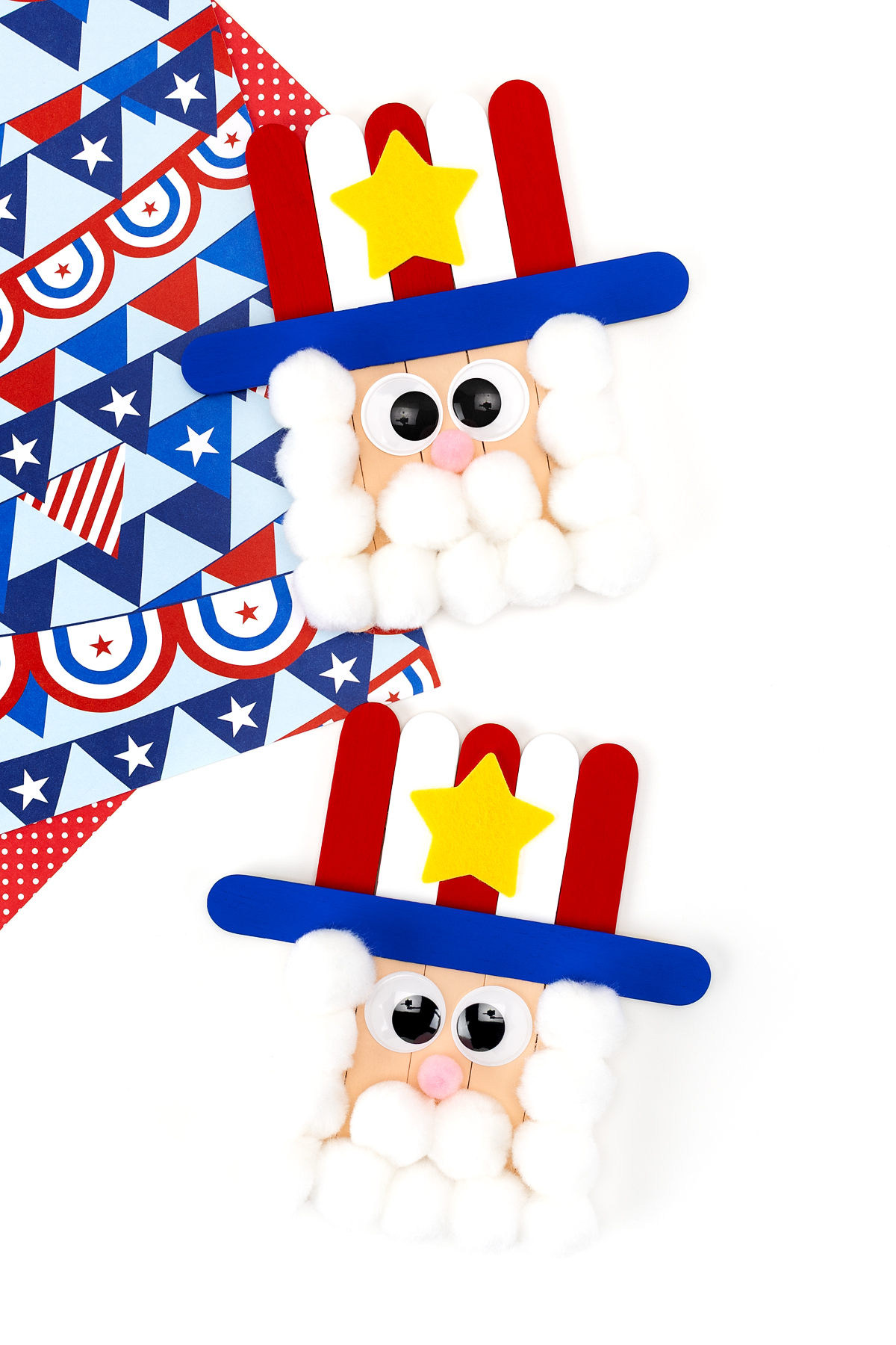 Two finished Uncle Sam popsicle stick crafts with red white and blue hats white pom pom beards and wiggle eyes.