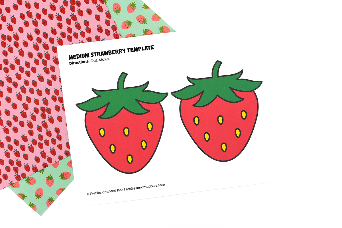 Pre-colored medium strawberry template printable with red strawberries and green leaves on white paper with a pink and green patterned background.