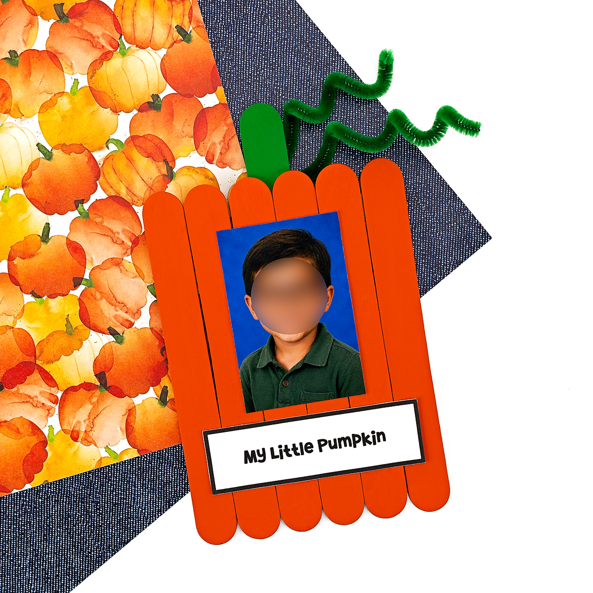 Popsicle stick pumpkin keepsake craft with child's photo and green pipe cleaner vine.