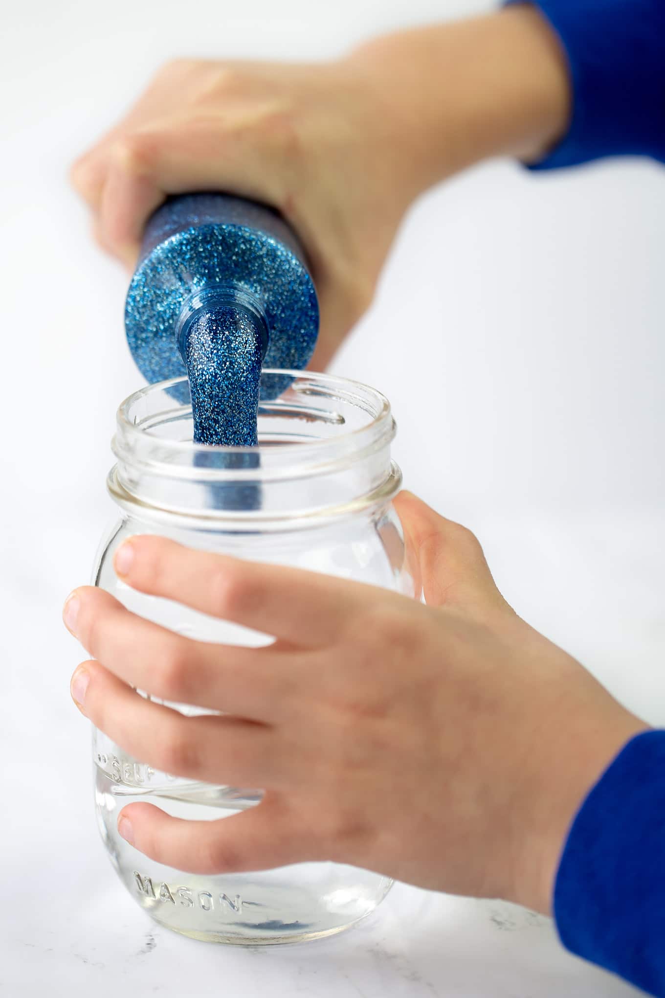 Child Pouring Glitter Glue Into Jar