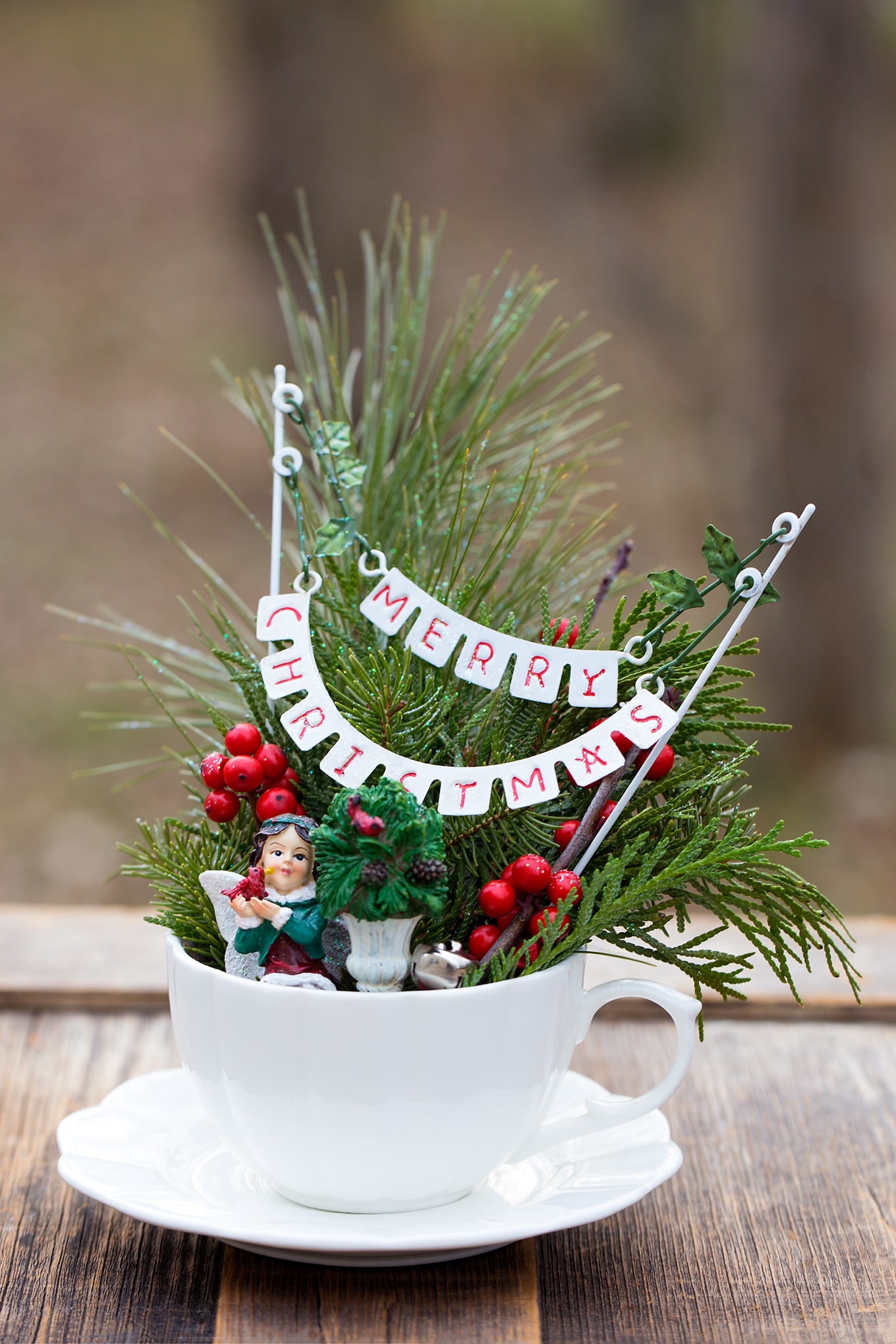 Just in time for Christmas, learn how to make a festive Christmas Teacup Garden with pine sprigs, winterberry, a teacup and saucer, and Christmas miniatures. #diychristmasgift #christmascrafts #teacupgarden #fairygardencrafts #christmasteacupgarden How to Make a Festive Christmas Teacup Garden