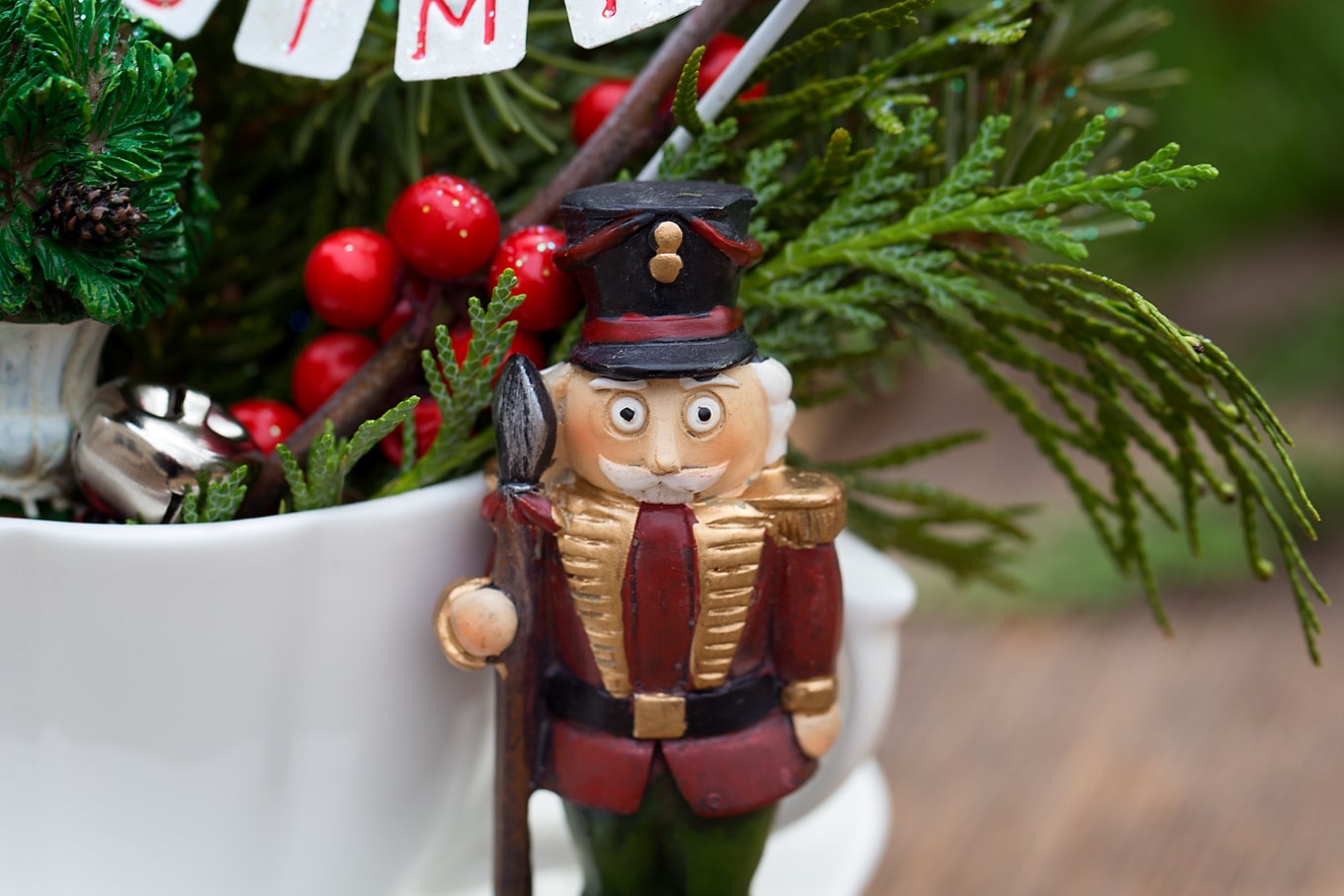 Just in time for Christmas, learn how to make a festive Christmas Teacup Garden with pine sprigs, winterberry, a teacup and saucer, and Christmas miniatures. #diychristmasgift #christmascrafts #teacupgarden #fairygardencrafts #christmasteacupgarden Resin Nutcracker in Christmas Teacup Garden