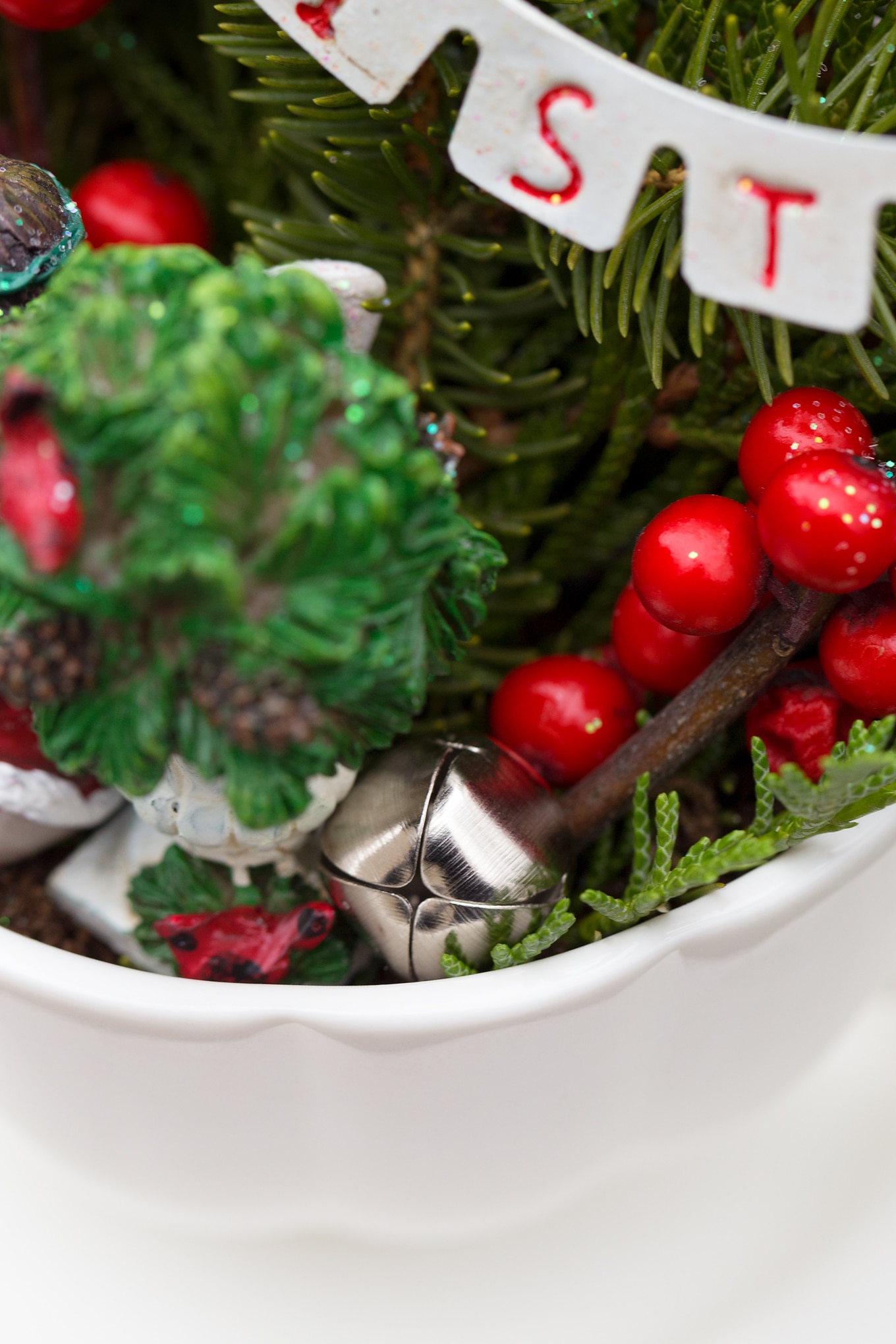 Just in time for Christmas, learn how to make a festive Christmas Teacup Garden with pine sprigs, winterberry, a teacup and saucer, and Christmas miniatures. #diychristmasgift #christmascrafts #teacupgarden #fairygardencrafts #christmasteacupgarden A Tiny Jingle Bell in a Christmas Teacup Garden