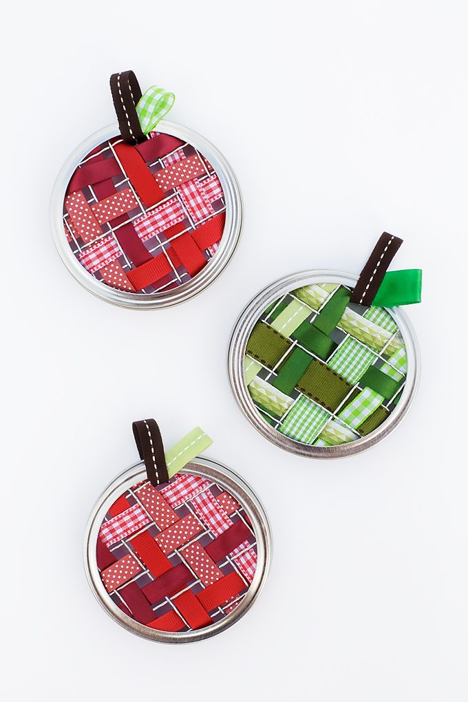 Celebrate apple season with colorful Scrap Ribbon Apple Suncatchers. They are made with mason jar frogs, rings, bits of scrap ribbon, and glue!