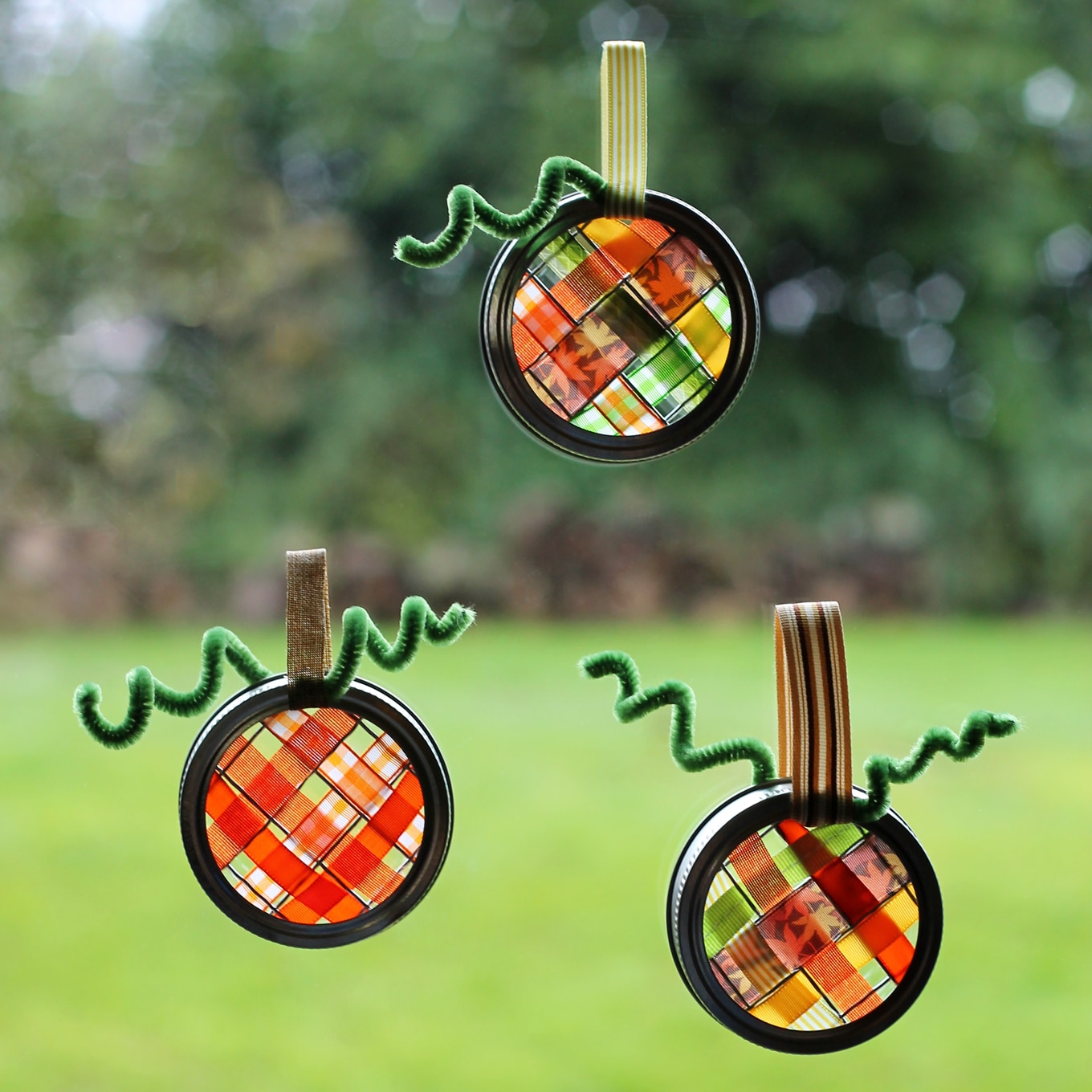 Just in time for fall, learn how to make vibrant pumpkin suncatchers with scraps of woven ribbon and mason jar lids. This weaving craft is perfect for kids!