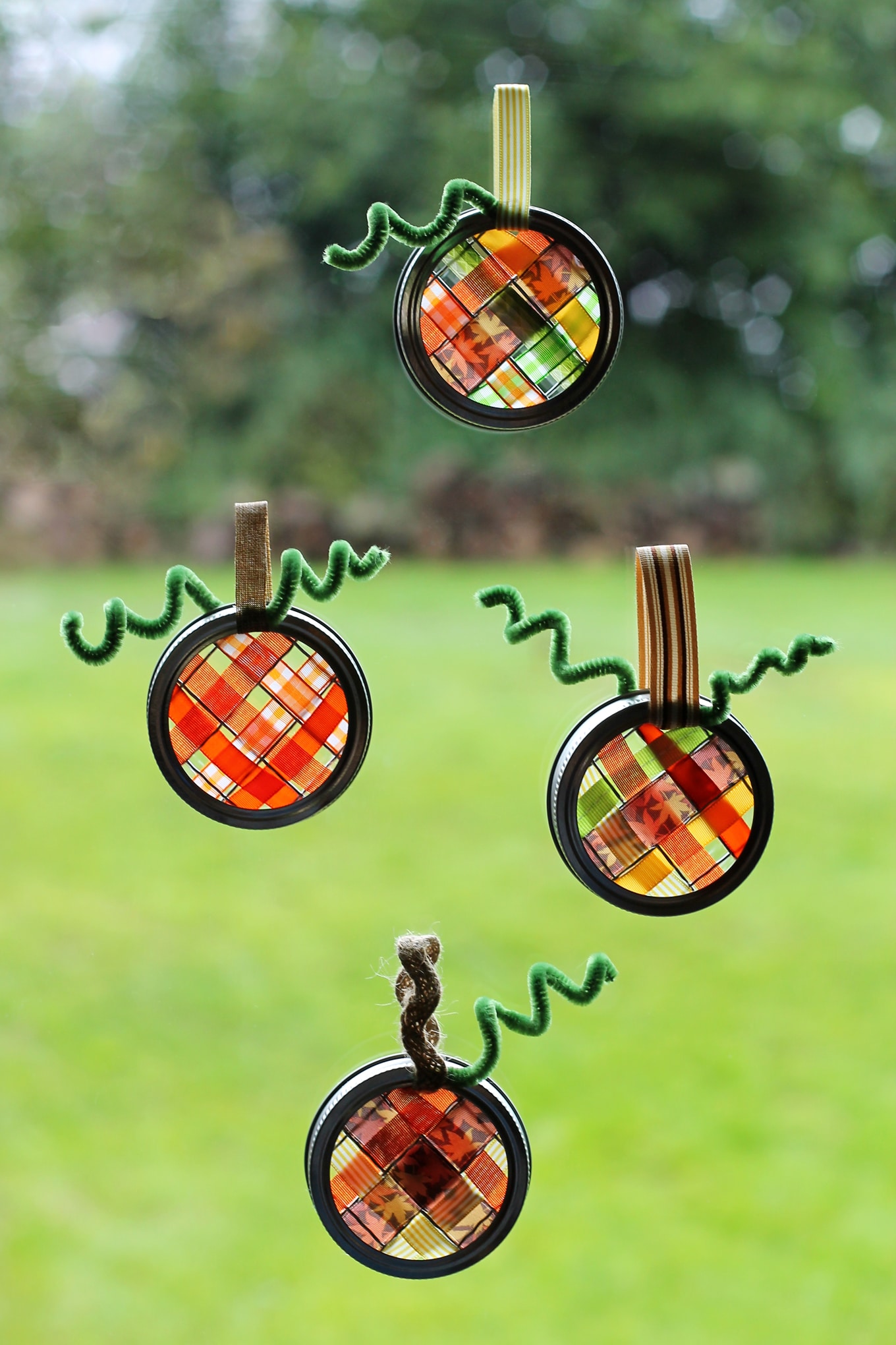 Just in time for fall, learn how to make vibrant pumpkin suncatchers with scraps of woven ribbon and mason jar lids. This weaving craft is perfect for kids!